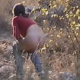 A low-quality, shaky video in which a woman pees in a natural setting outdoors. No audio.